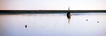 Comp image : ea00212 : Panoramic image showing a fishing boat returning from sea on a flat calm waterway - a thin strip of land in the background - on the coast of Suffolk, England