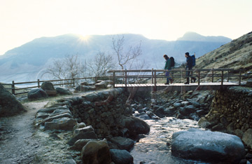 Comp image : ld00804 : Two walkers cross the footbridge over Stickle Ghyll on their way to Stickle Tarn in the English Lake District