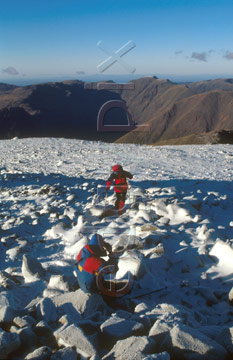 Comp image : ld04115 : Looking east from snow-covered Scafell Pike in the English Lake District, with two figures in red in low winter sunshine