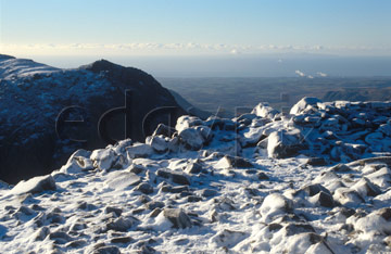 Comp image : ld04118 : Looking west from snow-covered Scafell Pike, in the English Lake District, in winter sun. Steam rising from Sellafield nuclear power station in the distance.