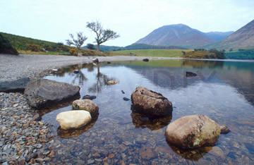 Comp image : ld05310 : Prominent rocks at the shore of Crummock Water, in the English Lake District, with a reflection of the distant fells in the background