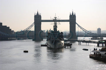 Comp image : lond010002 : HMS Belfast moored on the River Thames in London, with Tower Bridge in partial silhouette in the middle distance