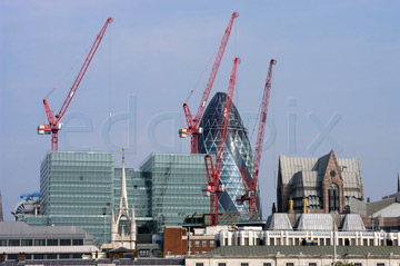 Comp image : lond010061 : London city skyline, with gaunt red construction cranes in the sunshine in front of Sir Norman Foster's 'gherkin', against a blue sky