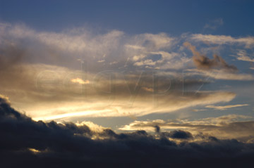 Comp image : sky020847 : A heavy band of ominous dark cloud in a blue sky in front of the setting winter sun