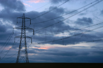 Comp image : sky020856 : Electricity pylon and cables silhouetted against stormy clouds, with a faint pink sunset glow