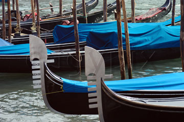 Comp image : ven021289 : Bow 'flags' (ferri) and blue covers of gondolas moored on the Grand Canal in Venice, Italy. The six projections of the ferro symbolise the six districts (sestieri) of the city.