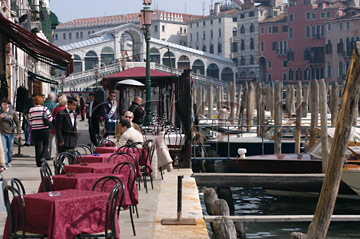 Comp image : ven021301 : Tables with red tablecloths at a cafe/restaurant by the Grande Canal [Canal Grande] in Venice, Italy, with the Rialto Bridge in the distance
