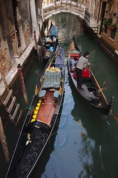 Comp image : ven021334 : Gondolas passing in a narrow canal in Venice, Italy, with a bridge in the background; one moored, the other with a gondolier