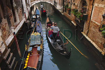 Comp image : ven021335 : Gondolas passing in a narrow canal in Venice, Italy, with a bridge in the background; one moored, two others with gondoliers line astern