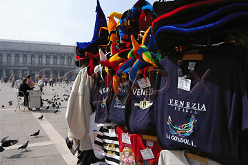 Comp image : ven021340 : Colourful carnival hats and T-shirts on a stall in sunny St Marks Square [Piazza San Marco] in Venice, Italy, with a pigeon-food seller in the background