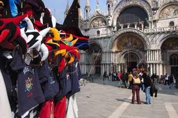 Comp image : ven021343 : Colourful carnival hats on a stall in St Marks Square [Piazza San Marco] in Venice, Italy, with tourists outside the Basilica San Marco in the background