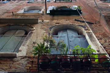 Comp image : ven021482 : Looking up steeply at the windows and windowboxes of an old red brick building in Venice, Italy, with the damage caused by Venetian damp easily visible