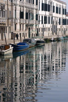 Comp image : ven021509 : Long reflections of grey buildings lining a canal in the Cannaregio area of Venice, Italy, with a line of boats in the mid distance