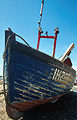 Bow view of an old blue fishing boat with worn paint in heavy shadow against a clear blue sky Bow view of an old blue fishing boat with worn paint in heavy shadow against a clear blue sky