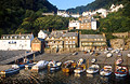 Fishing boats in the small harbour at Clovelly, Devon, England, with the buildings of the village on the steep hill in the background