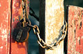 Padlock and chain on old peeling red and white painted gates Padlock and chain on old peeling red and white painted gates