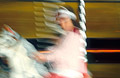 Blurred image of a girl on a horse on a fairground carousel
