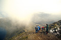 Walkers look down through low cloud to Striding Edge from Hellvellyn, in the English Lake District