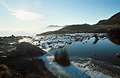 Bright winter sun over the icy edge of Stickle Tarn, Langdale, in the English Lake District