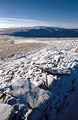 Snow covers a stone wall on High Street, east of Hartsop, in the English Lake District. Thornethwaite Crag under a blue sky in the distance.