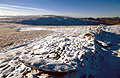 Snow covers a stone wall on High Street, east of Hartsop, in the English Lake District. Thornethwaite Crag under a blue sky in the distance.