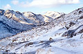 Snow-covered Crinkle Crags, Great Langdale, in the English Lake District, under a blue sky and winter sun, seen from the base of Great Knot