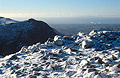 Looking west from snow-covered Scafell Pike, in the English Lake District, in winter sun. Steam rising from Sellafield nuclear power station in the distance.