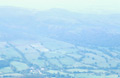 A delicate view through mist towards the patchwork fields around Loweswater, from Grasmoor, over Crummock Water in the English Lake District