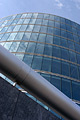 Dramatic view looking up at a curved glass London building reflecting the blue sky