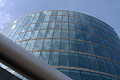 Dramatic view looking up at a curved glass London building reflecting the blue sky