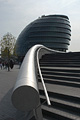 Dramatic view, against the light, looking along a curved wall and handrail to London's City Hall on the south bank of the River Thames