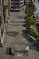 Aerial view of a single cyclist in white on the paved walkway beside the River Thames in London, England, with sun casting shadows on the paving