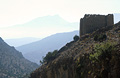 A Berber grain store building high on a hillside in the High Atlas mountains of Morocco, in partial silhouette against distant hills