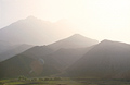 Looking into the early morning sun over M'Goun in the High Atlas mountains of Morocco, across nearer peaks and foreground meadows