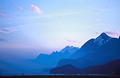 Wispy clouds in an evening sky over receding misty blue mountains in Switzerland