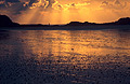 Reflection of a dramatic orange sunset in a wet stony sea shore at low tide