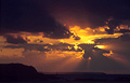 Dramatic orange rays of the sun tinting the dark clouds Dramatic orange rays of the sun tinting the dark clouds