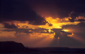 Dramatic orange rays of the sun tinting the dark clouds