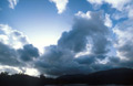 Dark cumulus clouds cover the evening sun over the silhouette of distant English hills