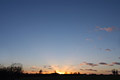 The last rays of the sun through wispy clouds on the skyline under a big deep blue clear sky