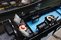 Looking down on a gondola on a canal in Venice, Italy; a straw gondolier's hat with a red ribbon lies on the seat, and part of another gondola is seen passing in the background