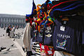 Colourful carnival hats and T-shirts on a stall in sunny St Marks Square [Piazza San Marco] in Venice, Italy, with a pigeon-food seller in the background