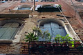 Looking up steeply at the windows and windowboxes of an old red brick building in Venice, Italy, with the damage caused by Venetian damp easily visible