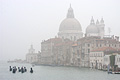 A fleet of gondolas on the Grand Canal [Canal Grande] in Venice, Italy, with the church of Santa Maria della Salute (1687) visible through the mist in the background
