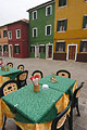 A colourful table outside a cafe on the island of Burano, Venice, Italy, matches the brightly painted buildings on the other side of the street