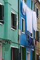 Washing hangs out to dry outside brightly painted green and blue houses on the island of Burano, Venice, Italy